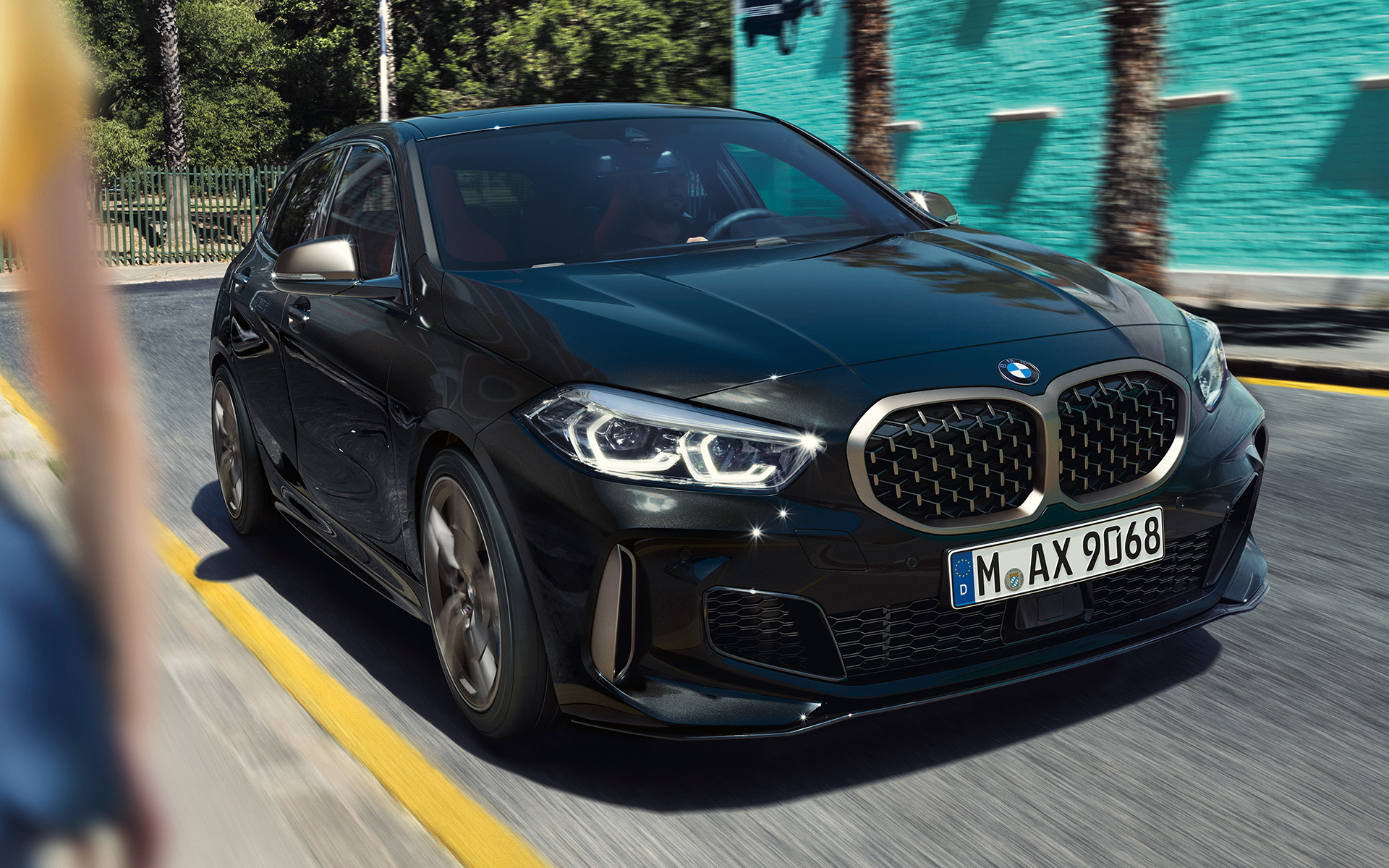 BMW M135i xDrive (F40) in Black Sapphire metallic, three-quarter front view driving