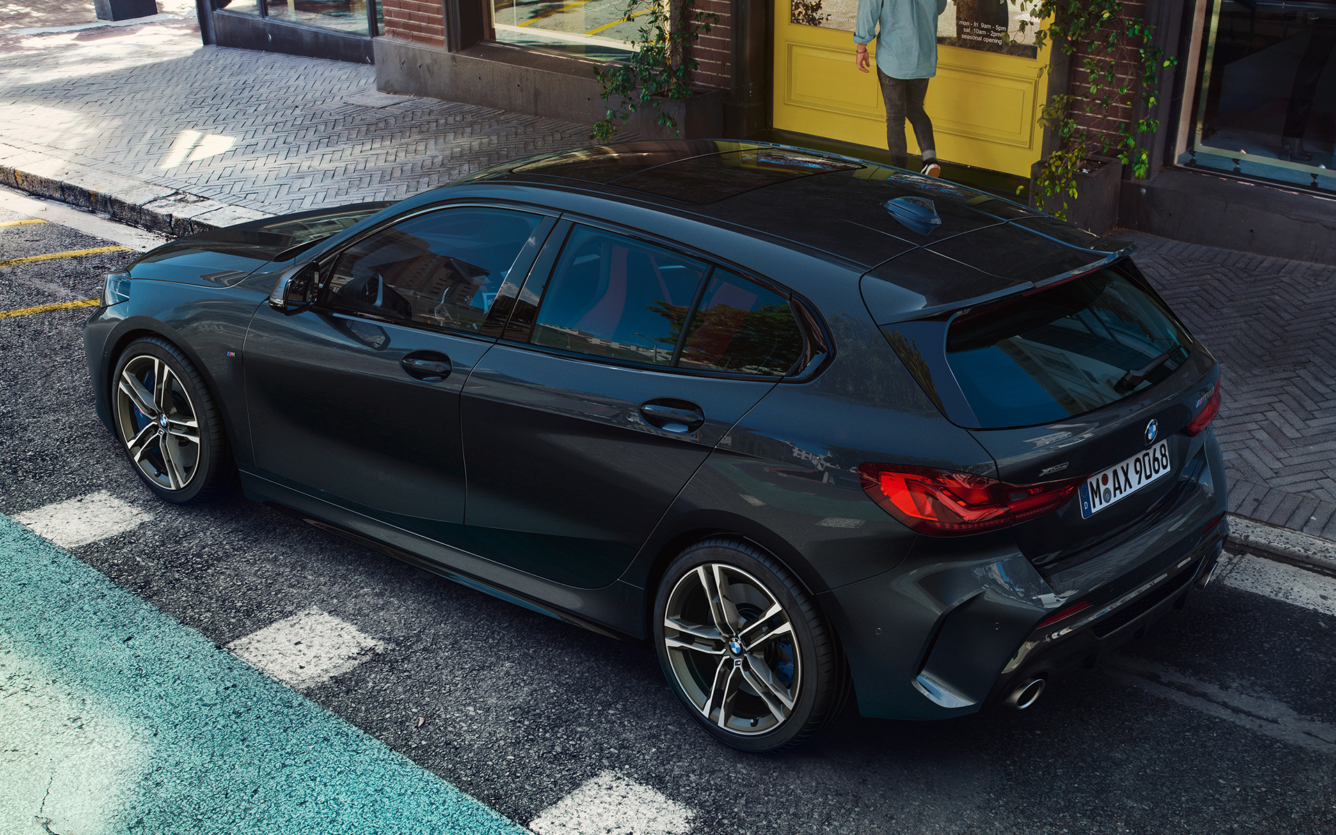 BMW M135i xDrive (F40) in Black Sapphire metallic parking, bird’s eye view of the side