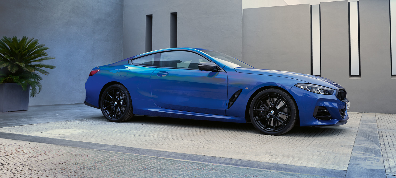 BMW M850i xDrive Coupé G15 LCI Facelift 2022 M Portimao Blue metallic side view standing in front of a building